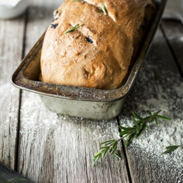 A homemade loaf of bread in a vintage bread pan on a wooden bench