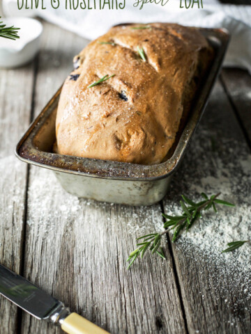A homemade loaf of bread in a vintage bread pan on a wooden bench