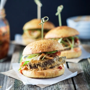 A front on image of a crispy mushroom burgers on a wooden board