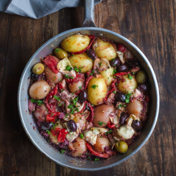 A skillet of potatoes and vegetables on a wooden bench