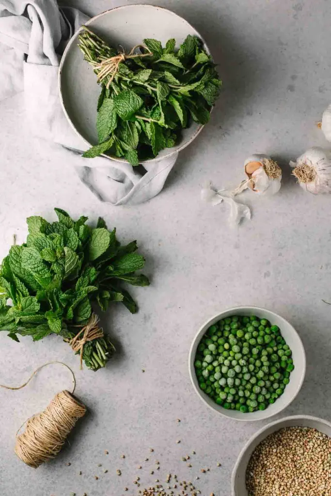 Overhead image of the green pea buckwheat risotto ingredients laid out on a grey textured surface. 