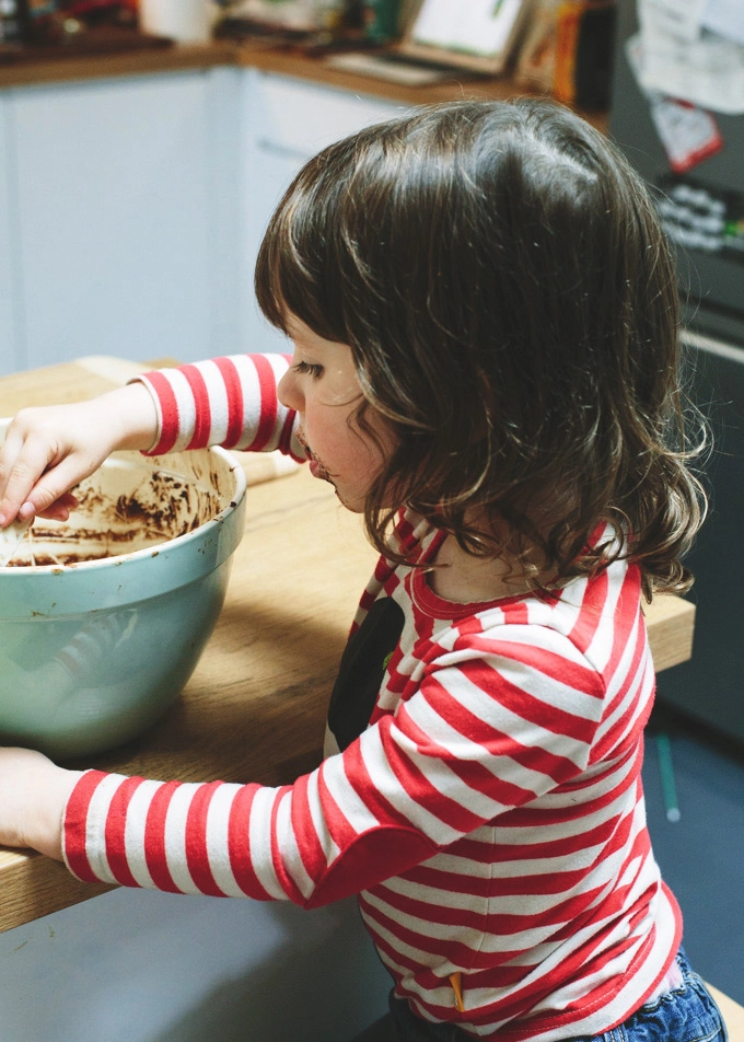 A little girl sitting at a table with a mixing bowl