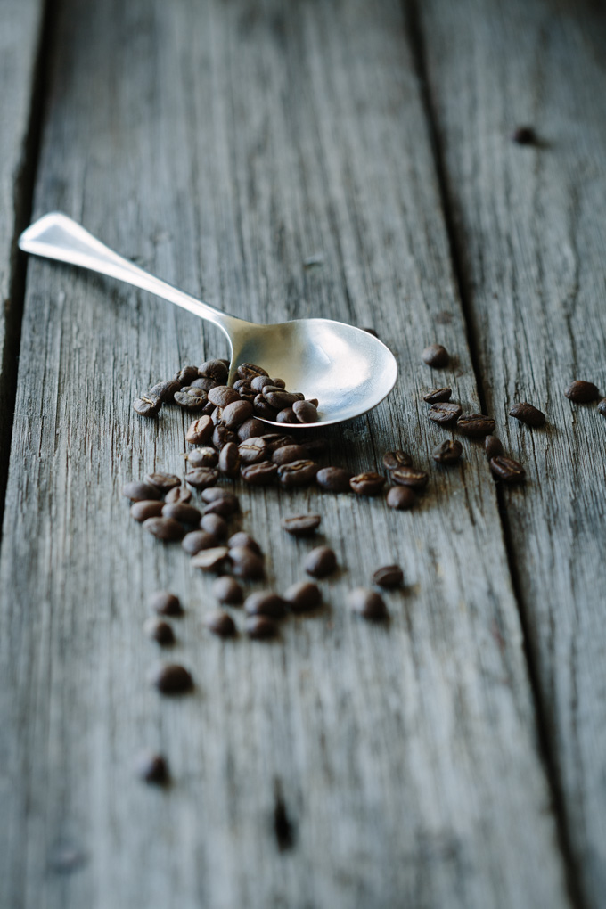 A spoon of espresso coffee beans on a wooden board