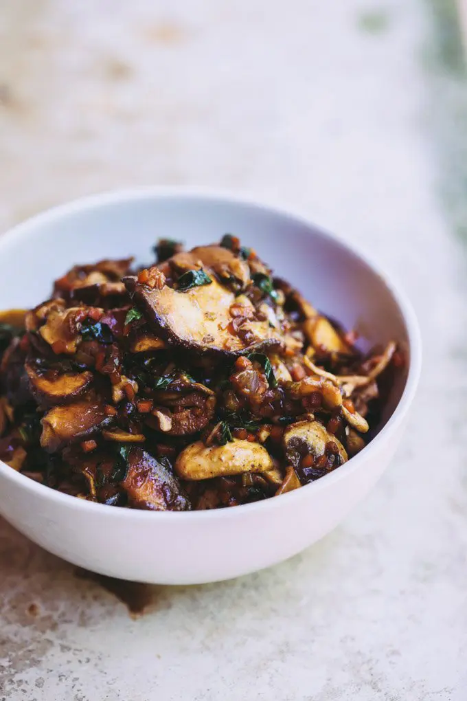 An angled image of a white bowl full of BBQ-style mushroom filling for the vegan bao buns