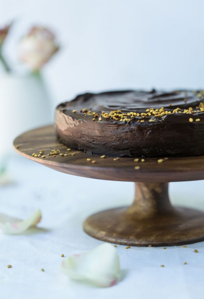 Raw chocolate cake on a wooden cake stand