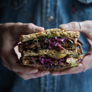 Close up of man holding reuben sandwich