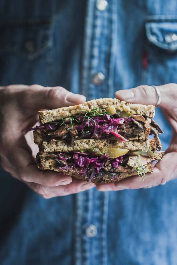 man holding vegan Reuben sandwich