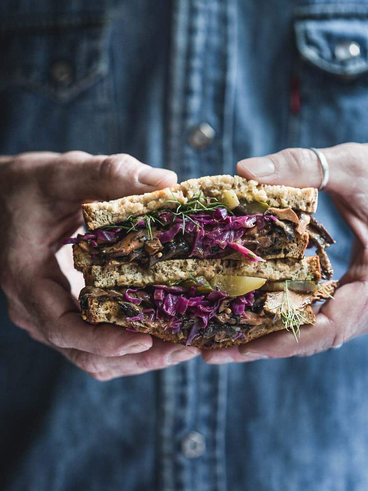 A man holding a Reuben Sandwich.