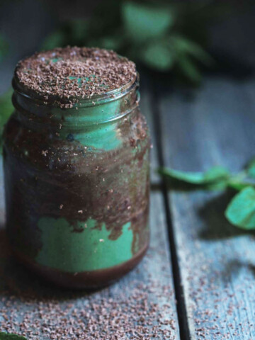 A close up of a jar of chocolate and mint smoothie with mint leaves