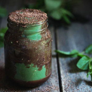 A close up of a jar of chocolate and mint smoothie with mint leaves