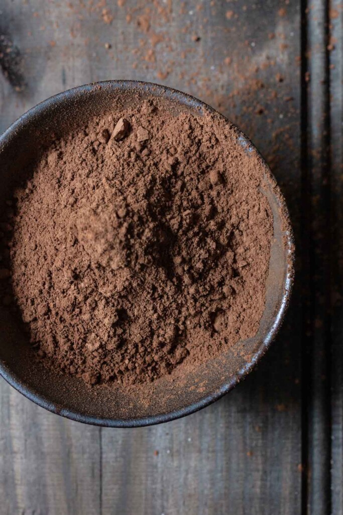 close-up process image of a bowl of raw cocoa measured to go in to the vegan chocolate beetroot cakes