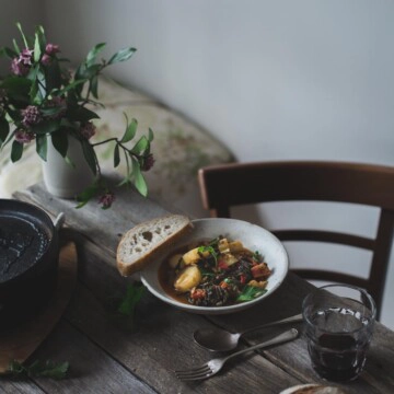 Potato and lentil stew in a white bowl on a rustic table setting.