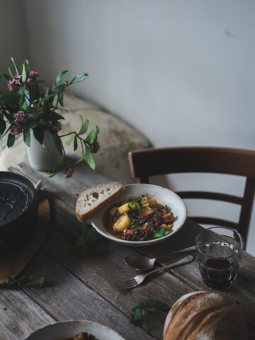 Potato and lentil stew in a white bowl on a rustic table setting.