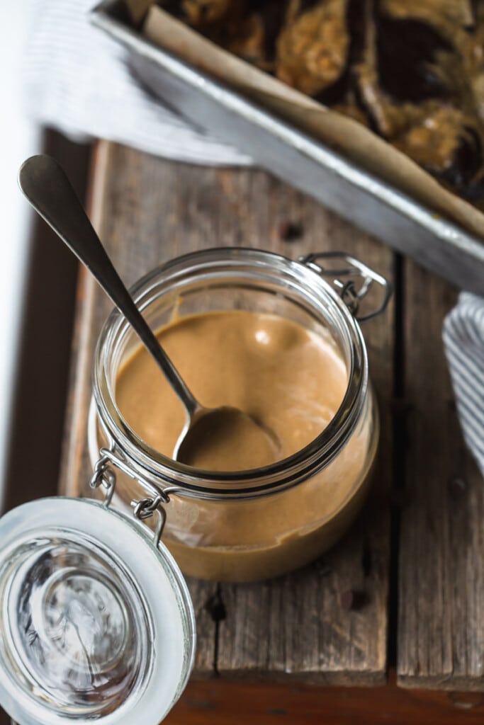 A jar of the tahini caramel sits on a wooden bench. 