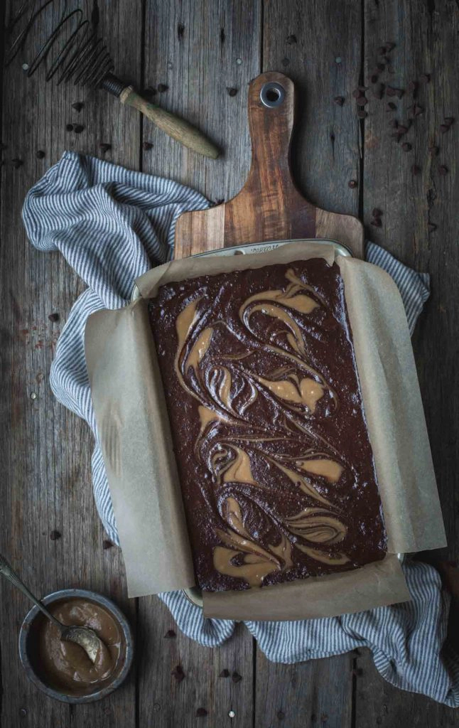 An overhead image of the black bean brownie batter in a brownie pan. The tahini caramel swirls have been done to show the pattern and correct consistency. 