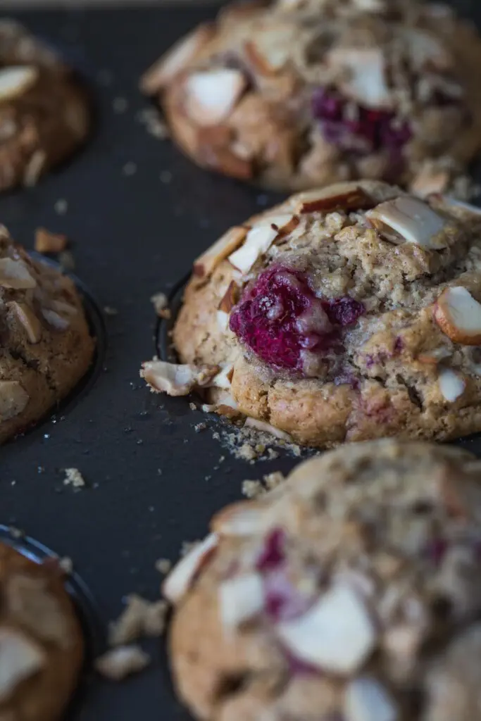 super close up image of vegan almond butter raspberry muffins in a baking tray