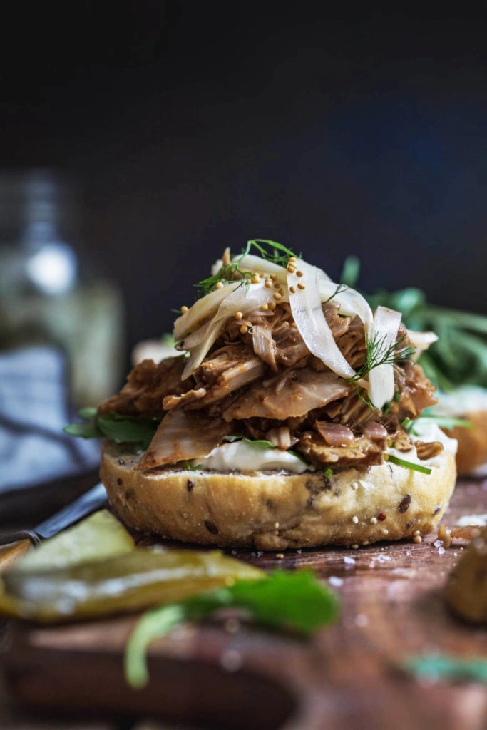 front on image of easy Creole jackfruit burger without it's bun top sitting on a wooden board with pickles in the foreground