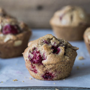 A close up image of a berry muffin on parchment paper.