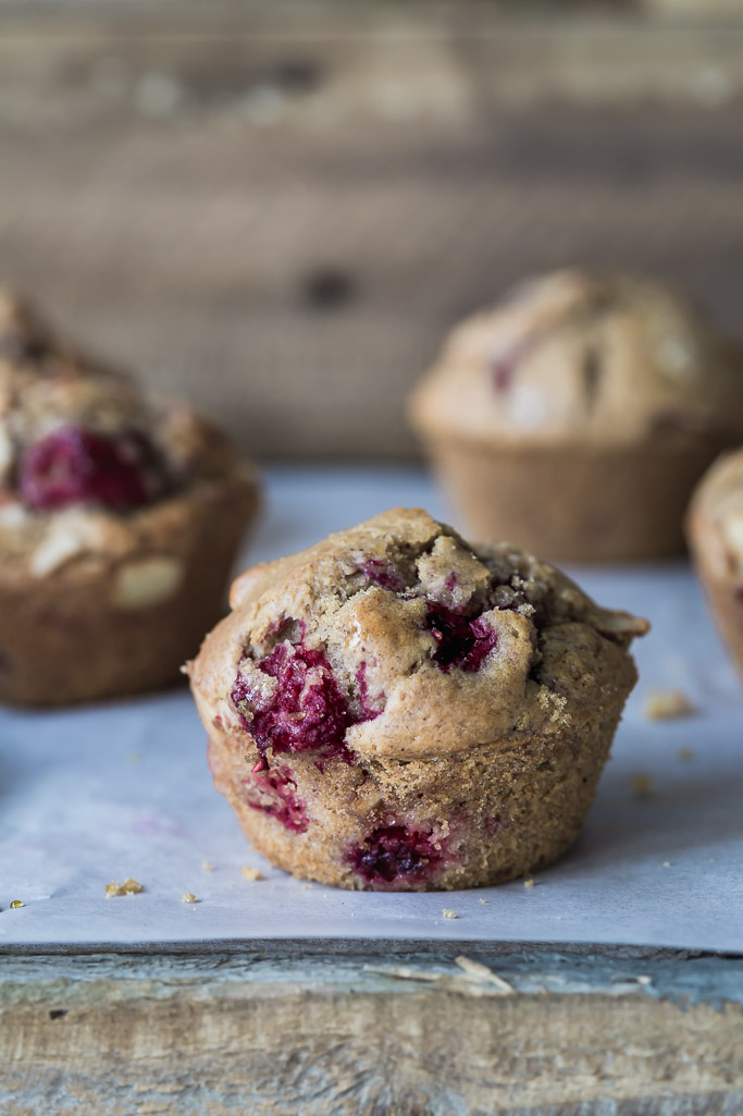 A close up image of a berry muffin on parchment paper. 
