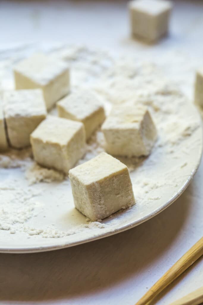 A close up image of the uncooked tofu rolled in the flour before being fried. 