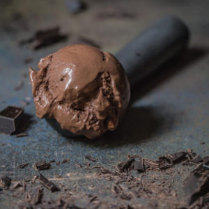 A scoop of vegan chocolate ice cream with a vintage ice cream scoop.