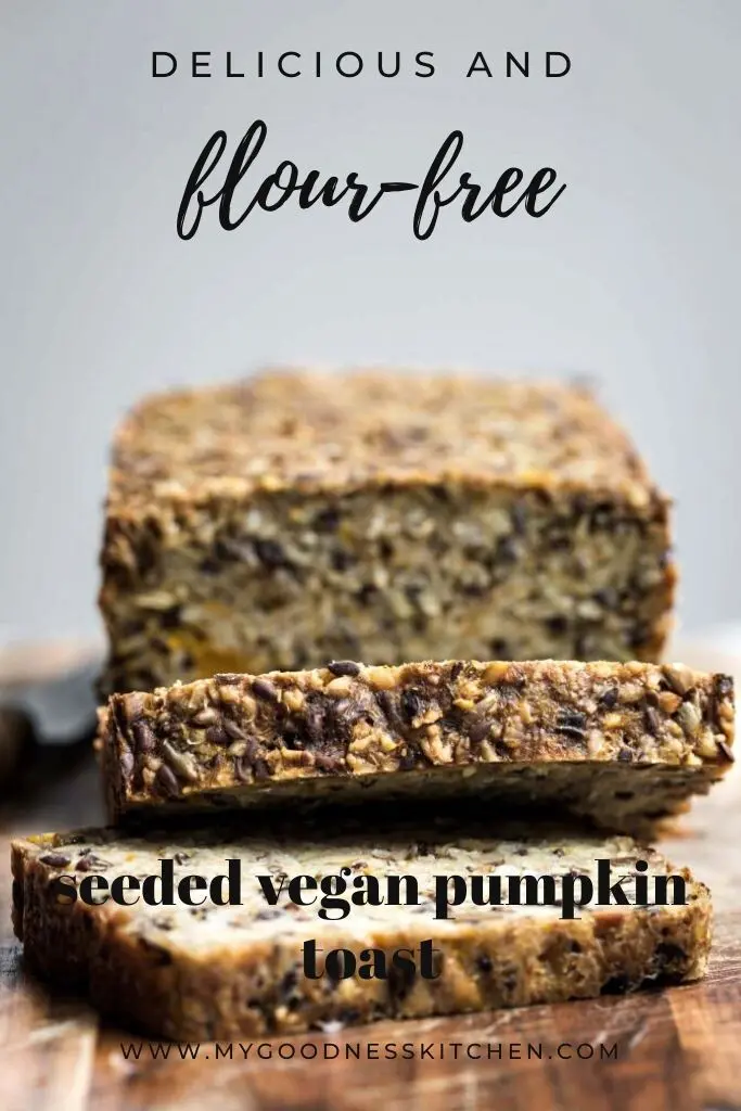 A close up image of vegan seeded pumpkin bread loaf sliced on a wooden board