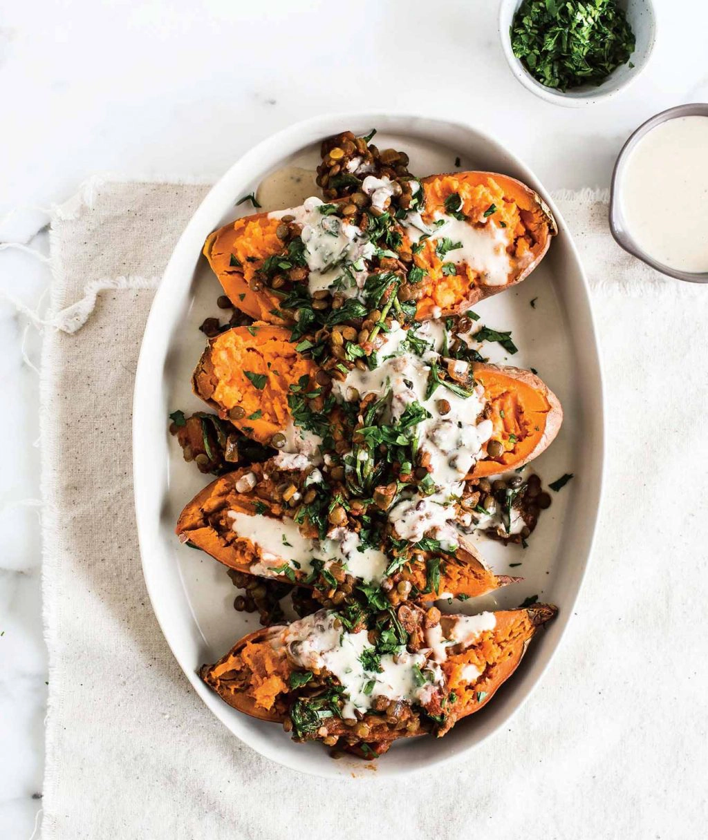 A white plate filled with roasted sweet potato and yoghurt dressing. 
