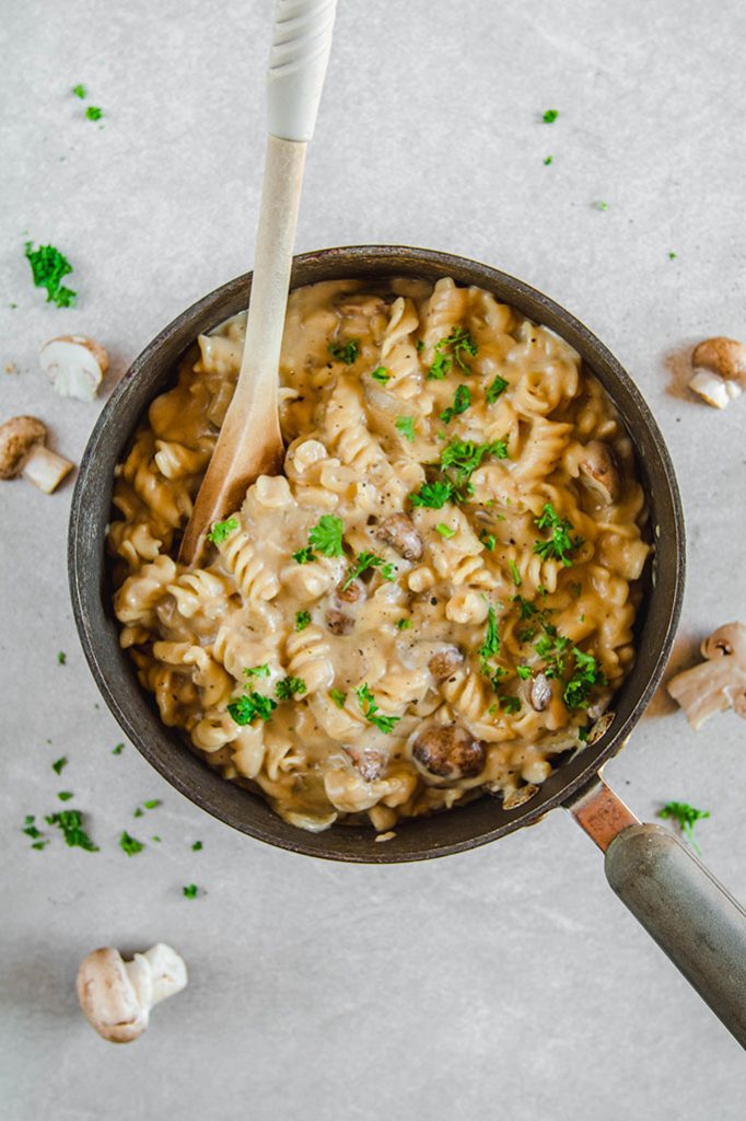 A saucepan full of vegan mushroom stroganoff with a wooden spoon
