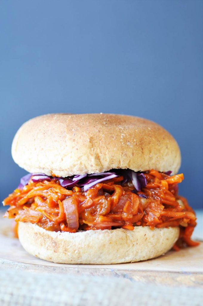 A pulled BBQ carrot burger against a light blue background