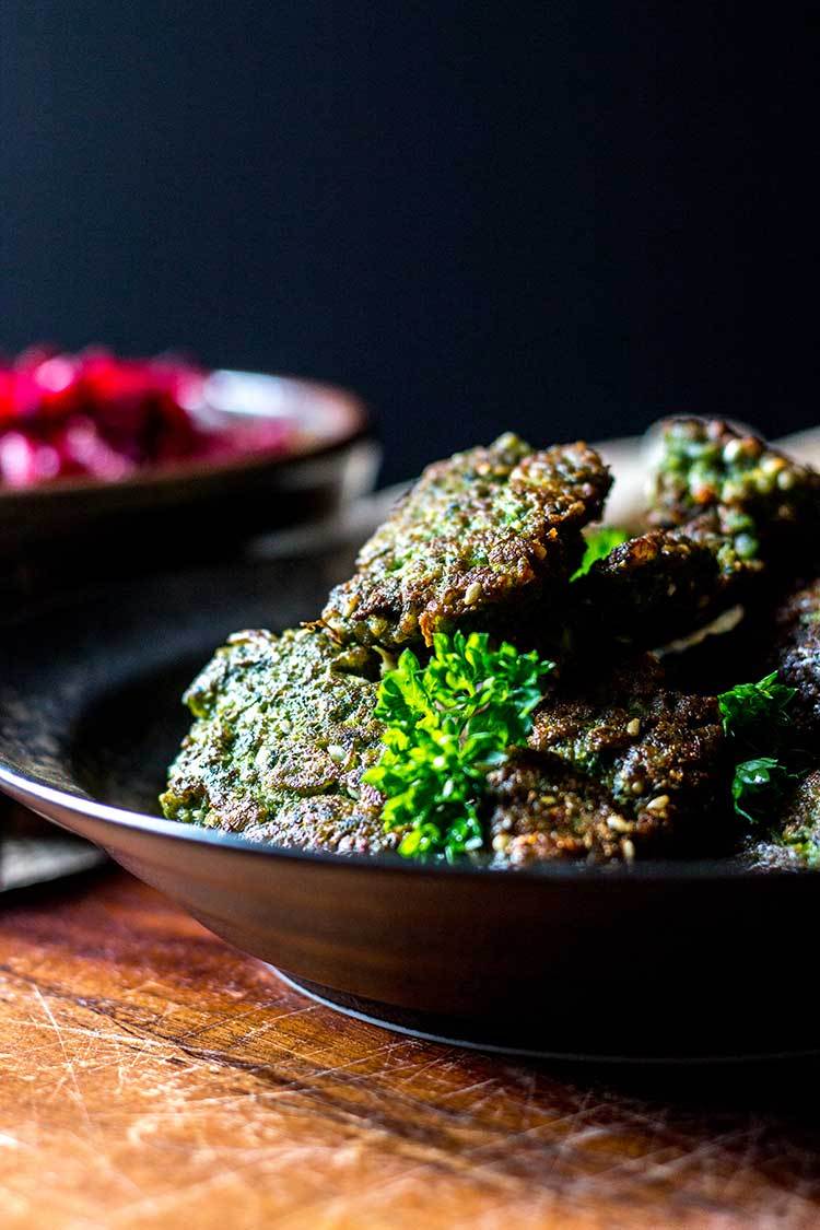 A black bowl full of broad bean falafel with tahini dressing