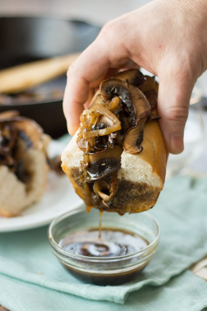 A hand holding a french dip sandwich 