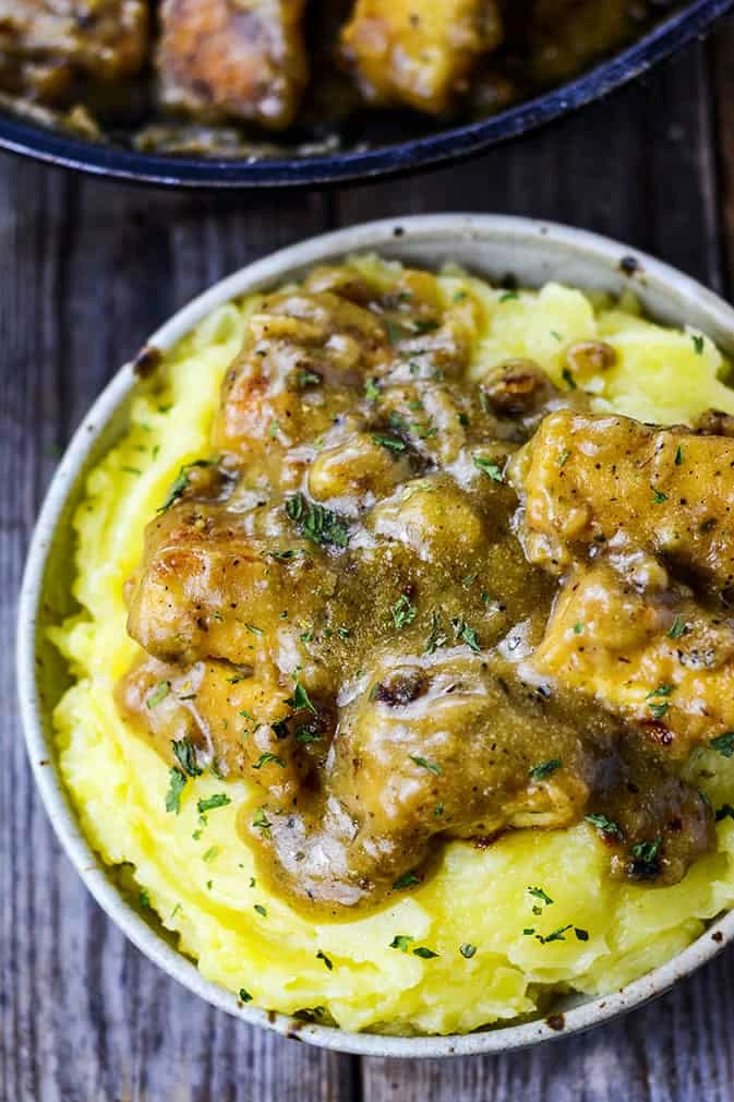 A white bowl of Smothered Tofu "Chicken" on mash