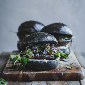 Three mushroom burgers on a wooden board.