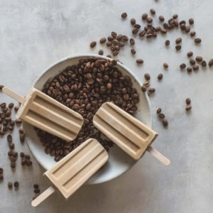 Milk coffee flavoured popsicles sitting in a bowl of coffee beans