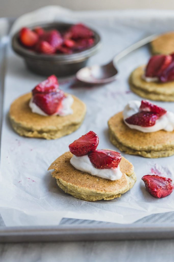 Banana and coconut pancakes with strawberries and cream on a tray