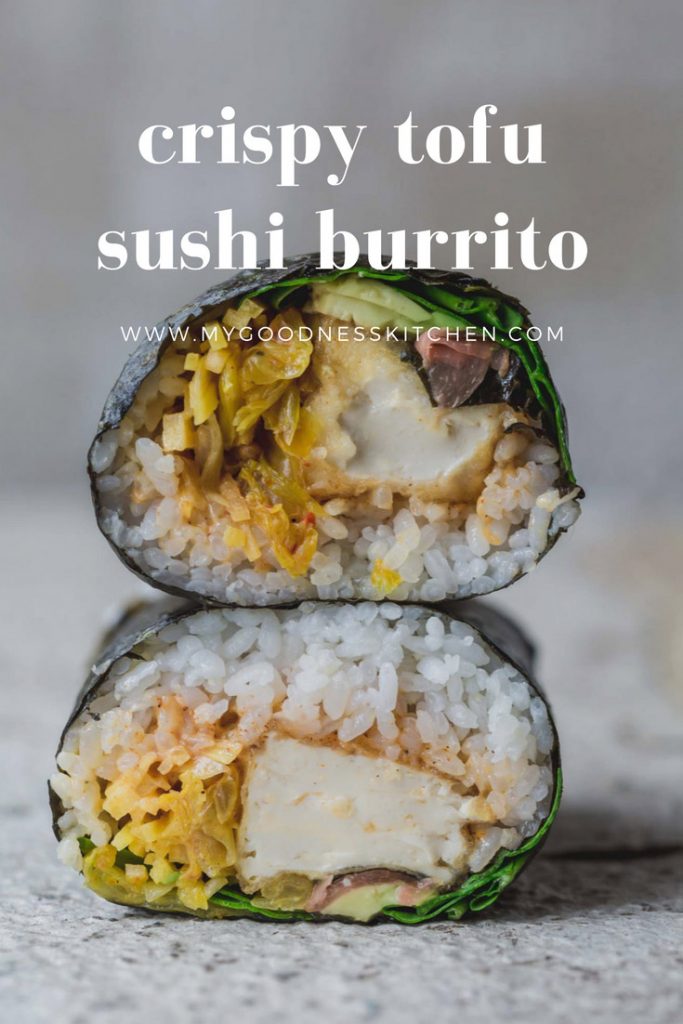 A vegan crispy tofu sushi burrito cut in half and stacked to show inside | sitting on rustic white bench with title text overlay