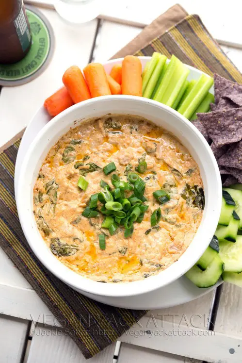 A bowl of dip with cucumber and corn chips. 