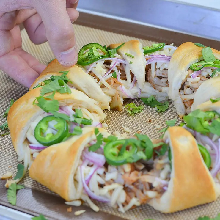 35 Vegan Party Food Recipes. No 3. Jackfruit Crescent Ring from Vegan Guide to the Galaxy sitting on a lined baking tray.