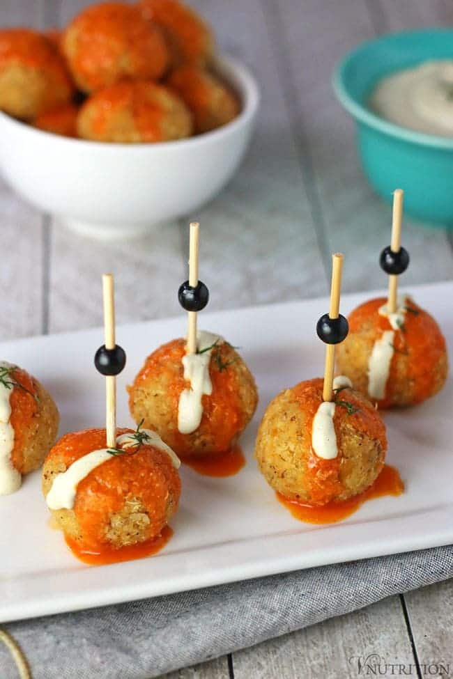 Savoury balls with sauce and toothpicks on a white plate. 