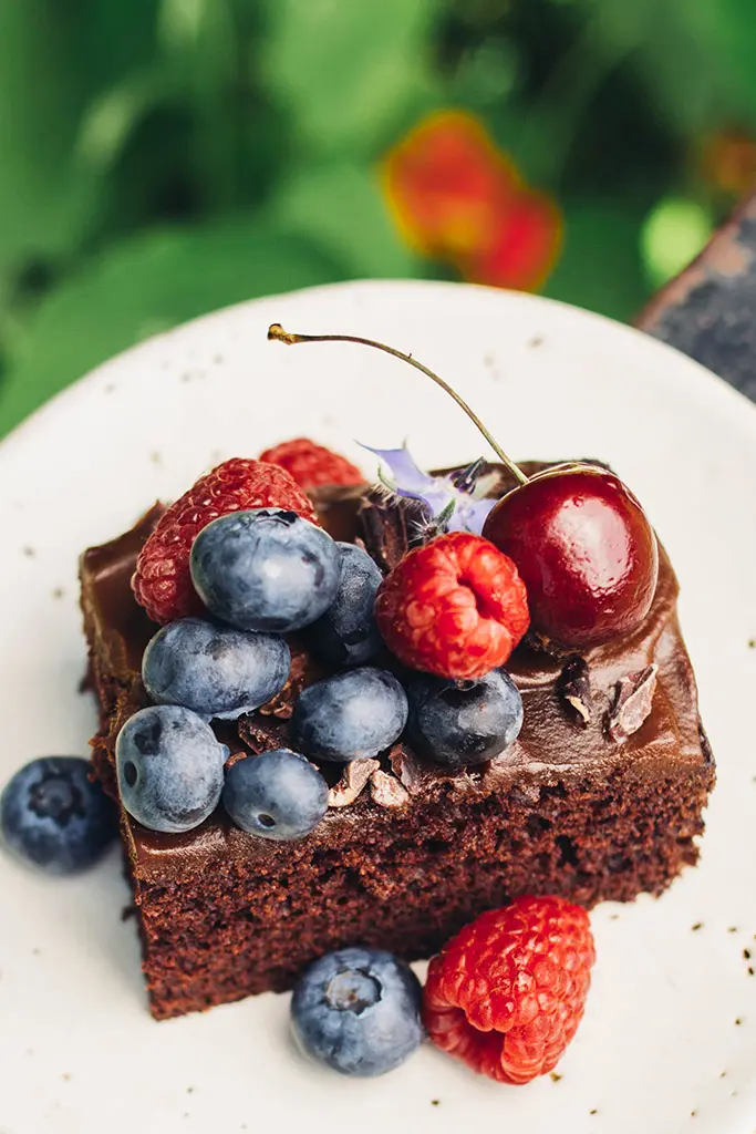 A slab of chocolate cake with berries. 