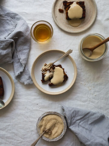 An overhead image of slices of pudding with brandy sauce on a table