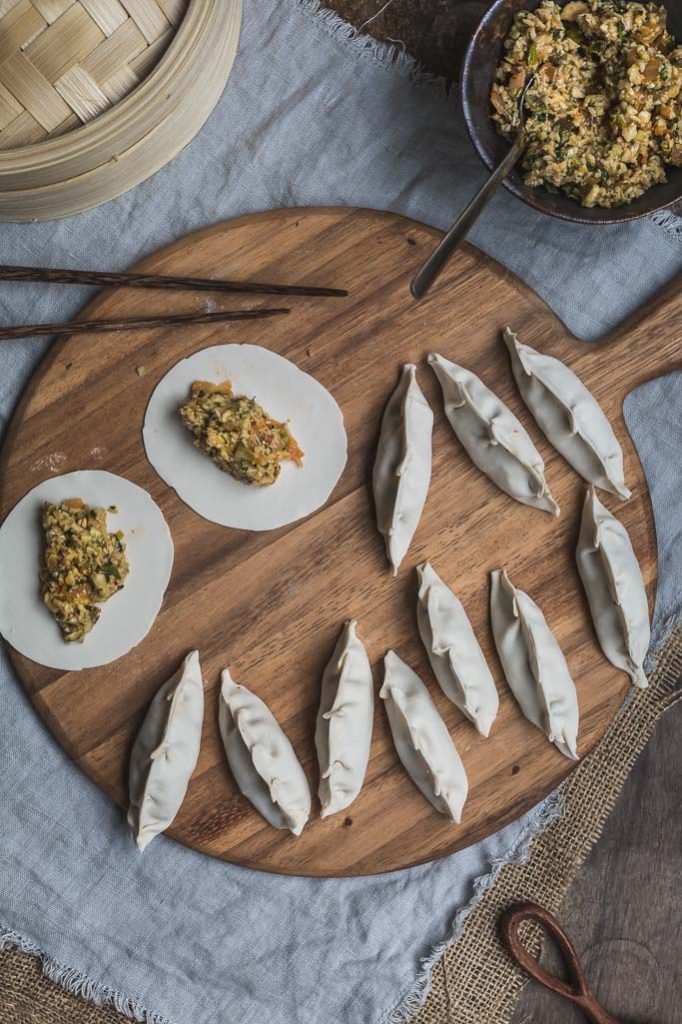 overhead image of recently made mushroom and kimchi dumplings on a round board