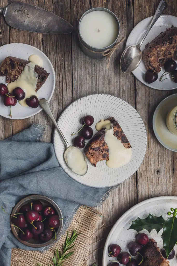 Overhead image of servings of vegan Christmas puddings on plates with fresh cherries