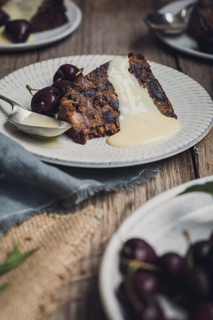 A close up image a single serve of vegan Christmas pudding with vegan brandy sauce