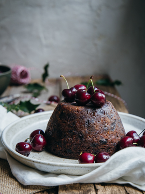 A Christmas pudding with cherries on a wooden table