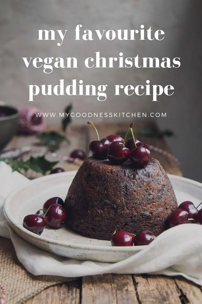 vegan Christmas pudding on serving plate with fresh cherries and text overlay