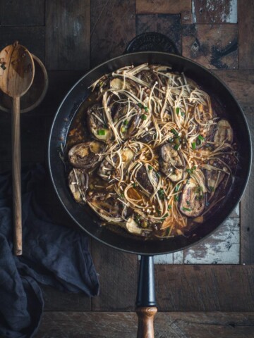 A noodle stir fry in a pan on a wooden table