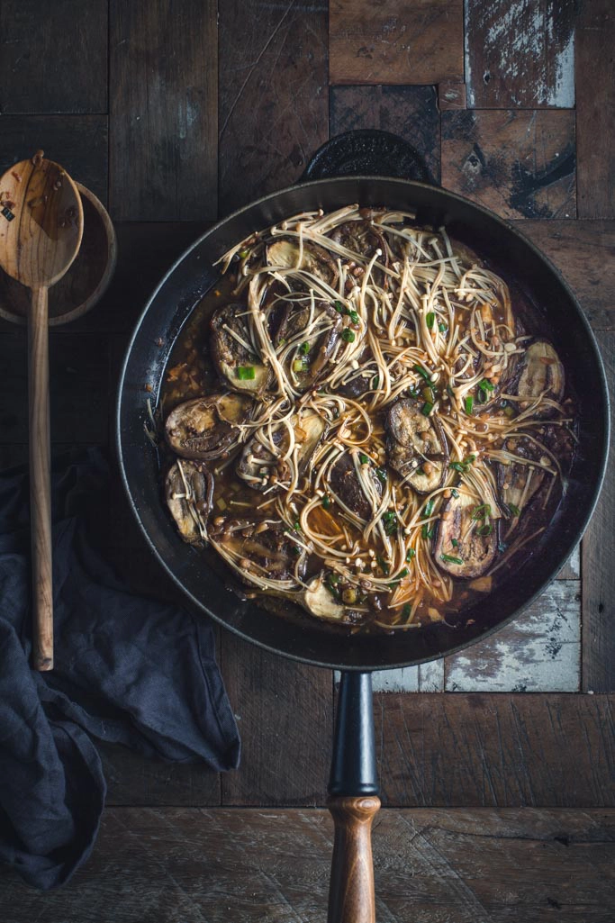 A noodle stir fry in a pan on a wooden table