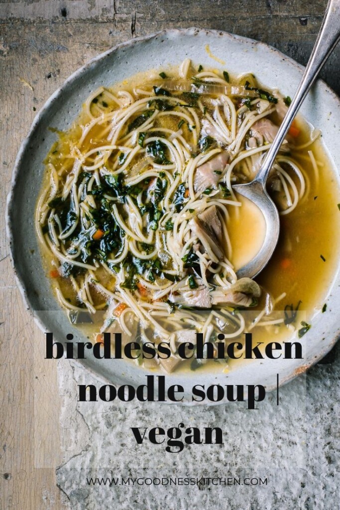 A close-up overhead image of a white bowl full of vegan chicken noodle soup with an antique spoon on a light wooden bench. Black text title overlay.