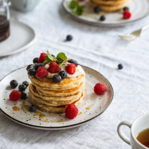 A close up of a plate of pancakes and berries on a table.